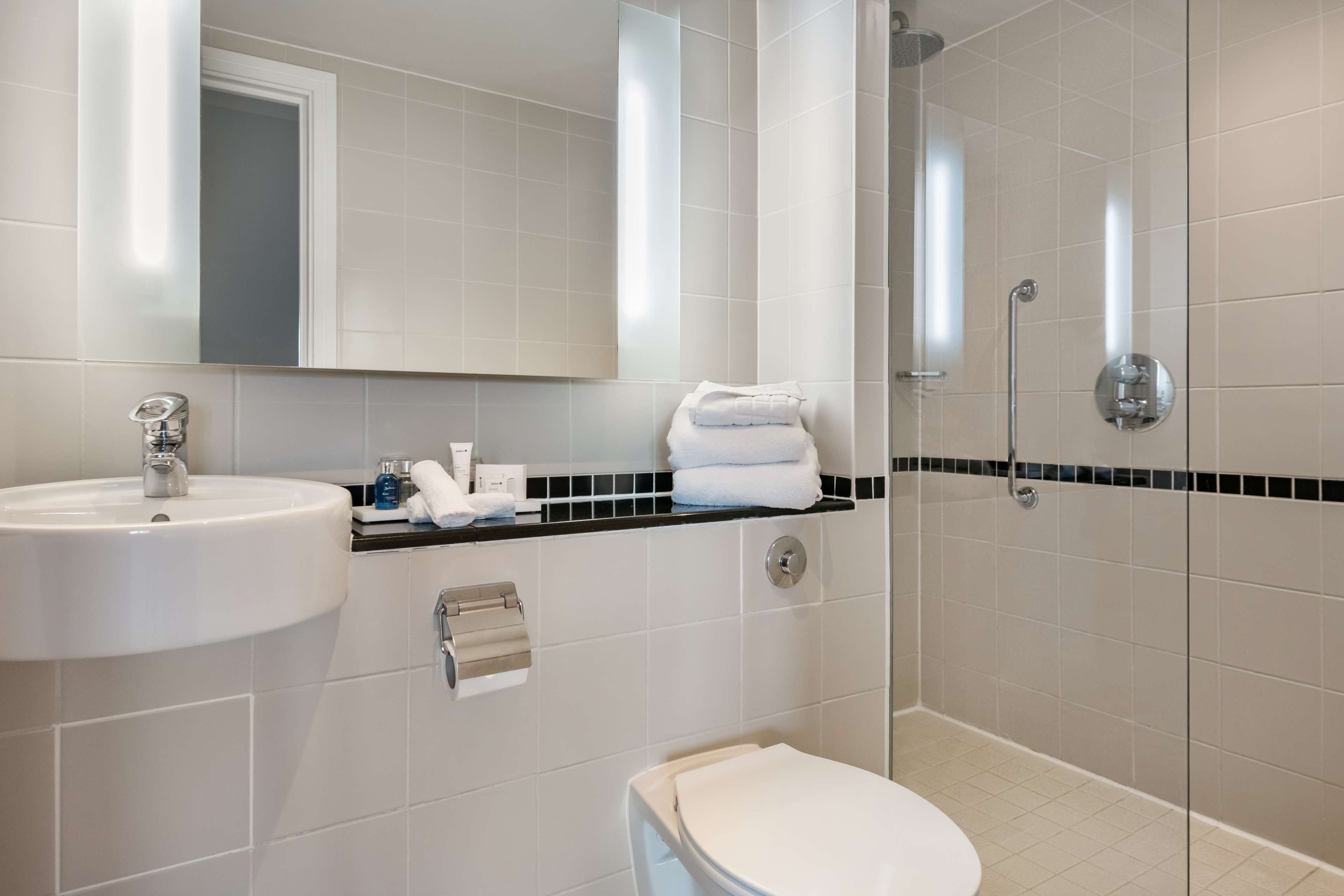 A modern bathroom with a sink, mirror, and toilet.