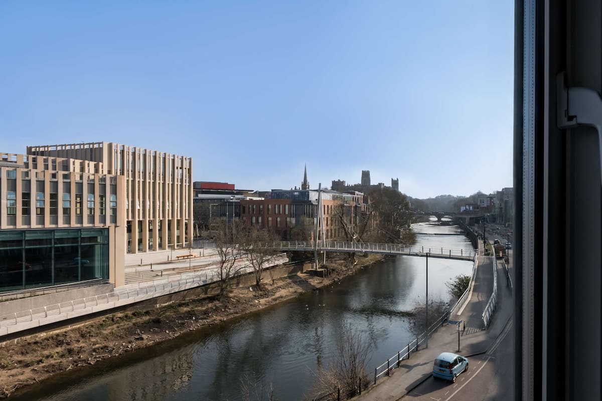 Un bâtiment moderne doté d’une façade en verre, avec une rivière qui le longe.