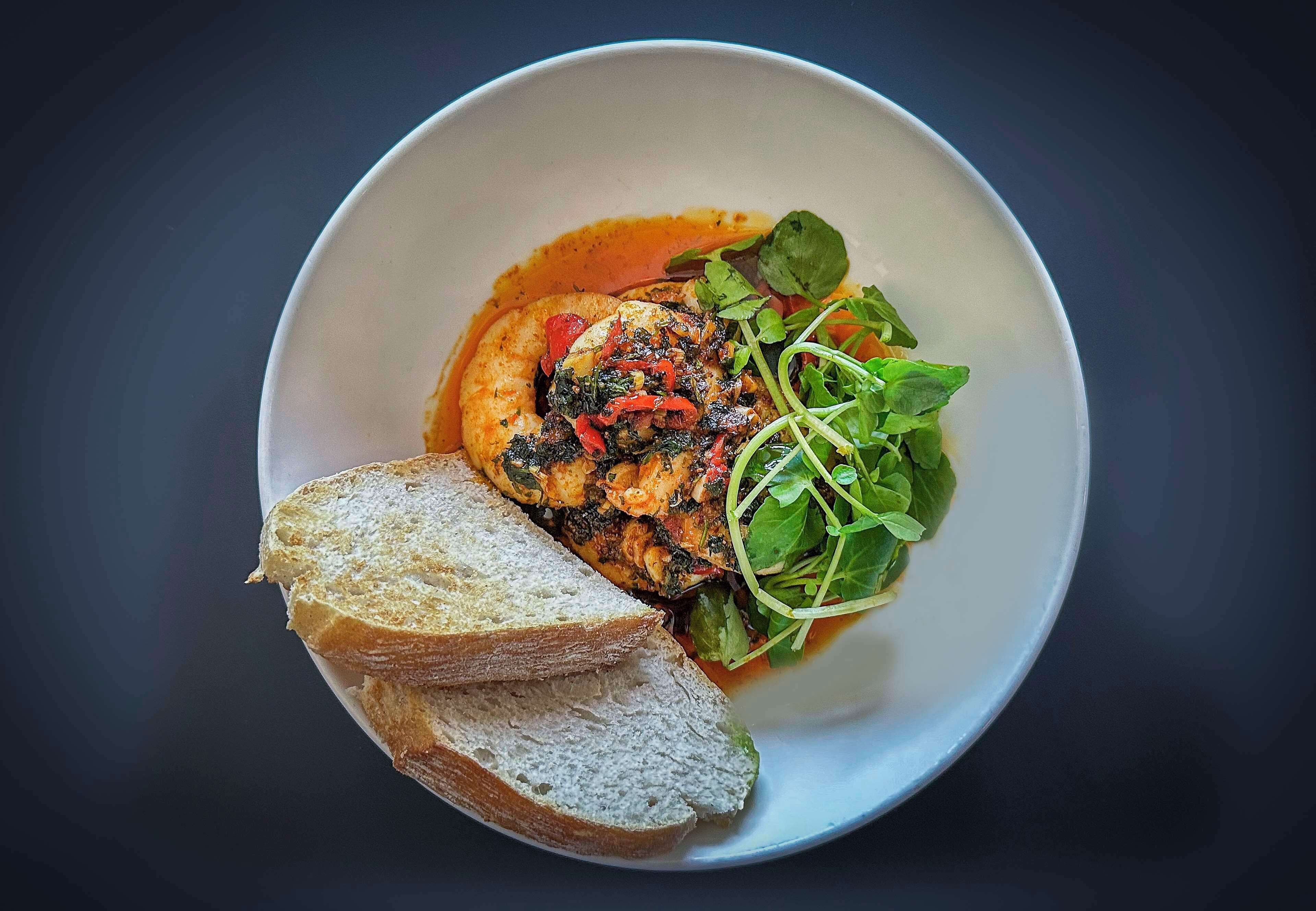A bowl of food with bread and greens.