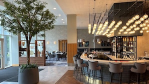A modern bar area with a central island, bar stools, and a large potted tree.