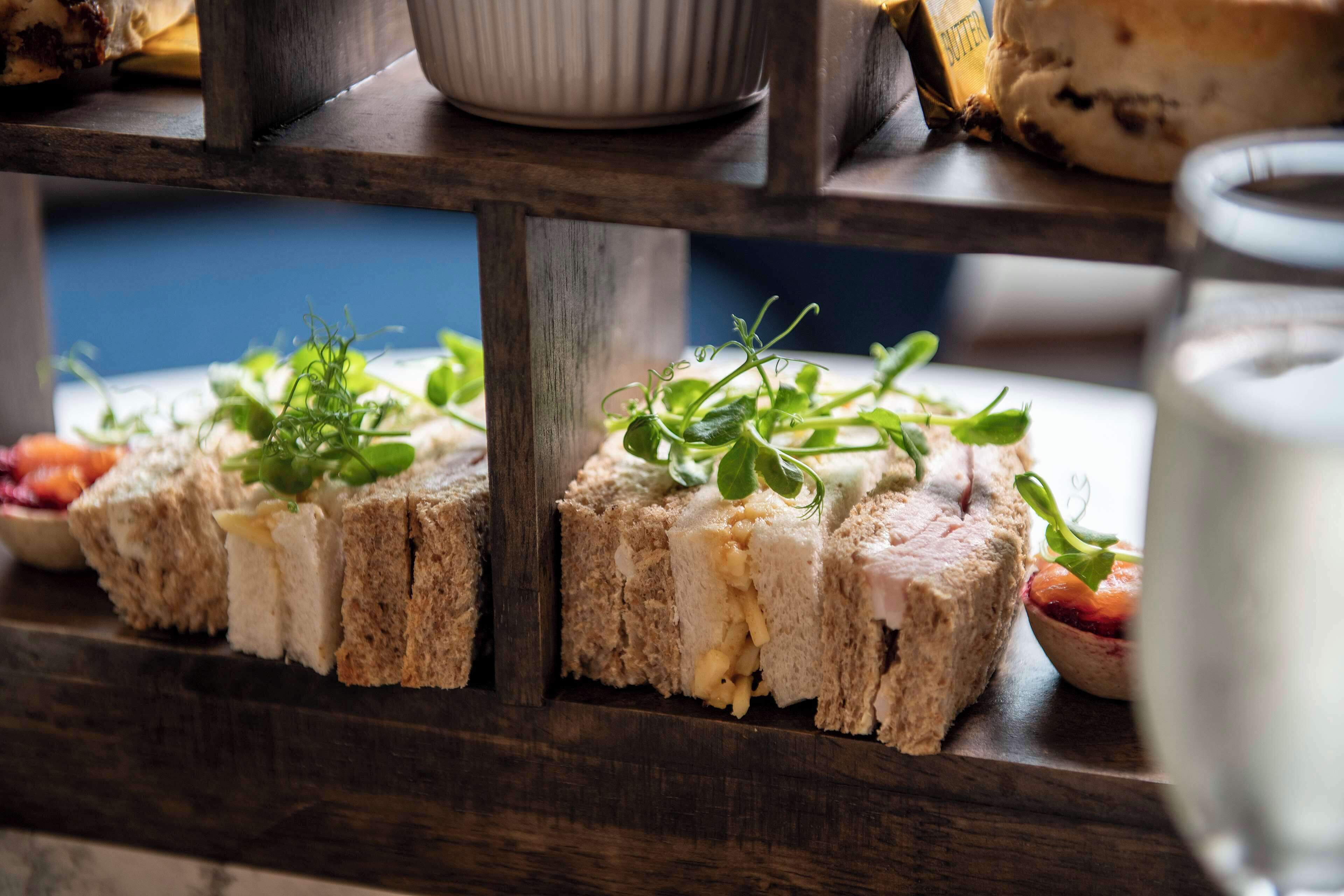 A wooden shelf with various food items, including sandwiches and a bowl of fruit.