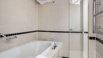Un baño moderno con bañera, cabina de ducha de vidrio y perchero para toallas.