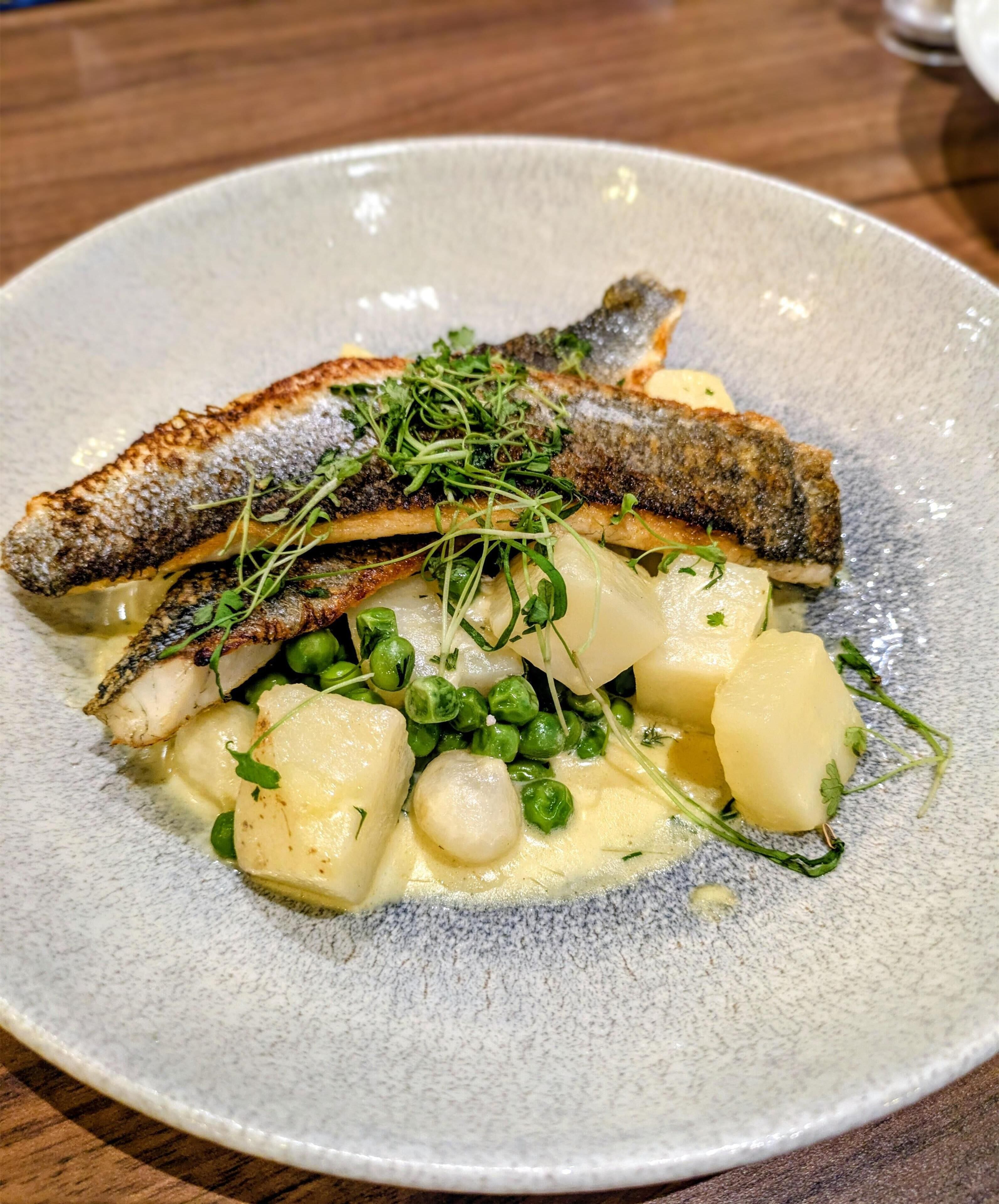 A plate of food with fish, peas, and potatoes.