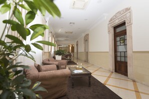 A hotel lobby with a sofa set, a coffee table with drinks, and a door with a decorative glass panel. - Hotel Cavaliere (Noci)