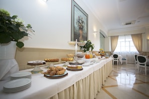A buffet table with various food items and a potted plant. - Hotel Cavaliere (Noci)