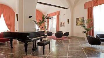 Un soggiorno spazioso con un pianoforte a coda, posti a sedere comodi e una grande finestra con tende.