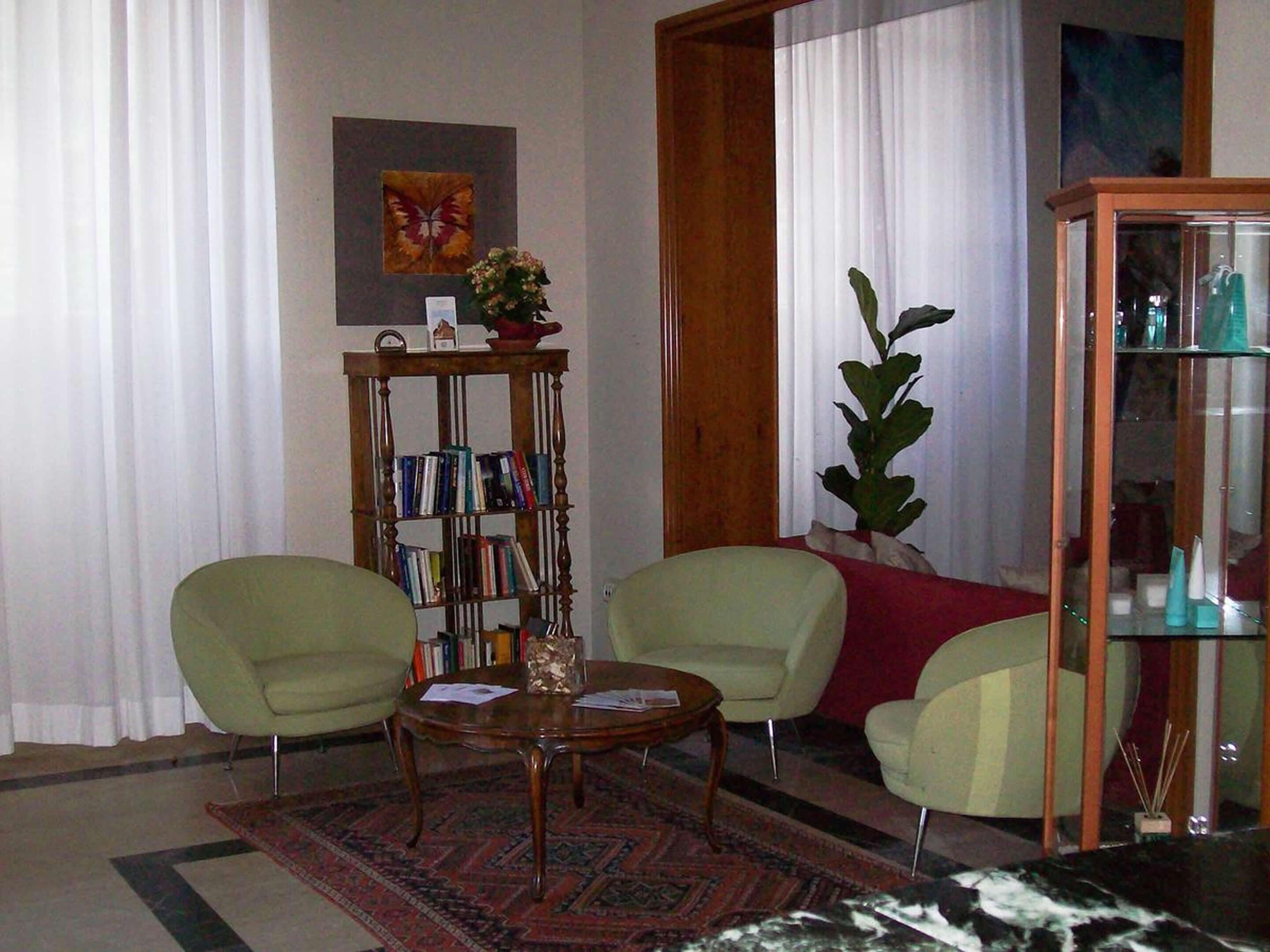 A living room with two armchairs, a coffee table, a bookshelf, and a glass cabinet.