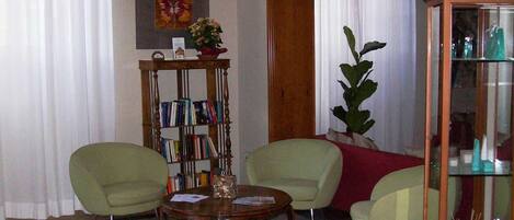 A living room with two armchairs, a coffee table, a bookshelf, and a glass cabinet.