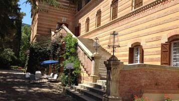 A building with a stone staircase leading to a door, surrounded by greenery and a blue umbrella.