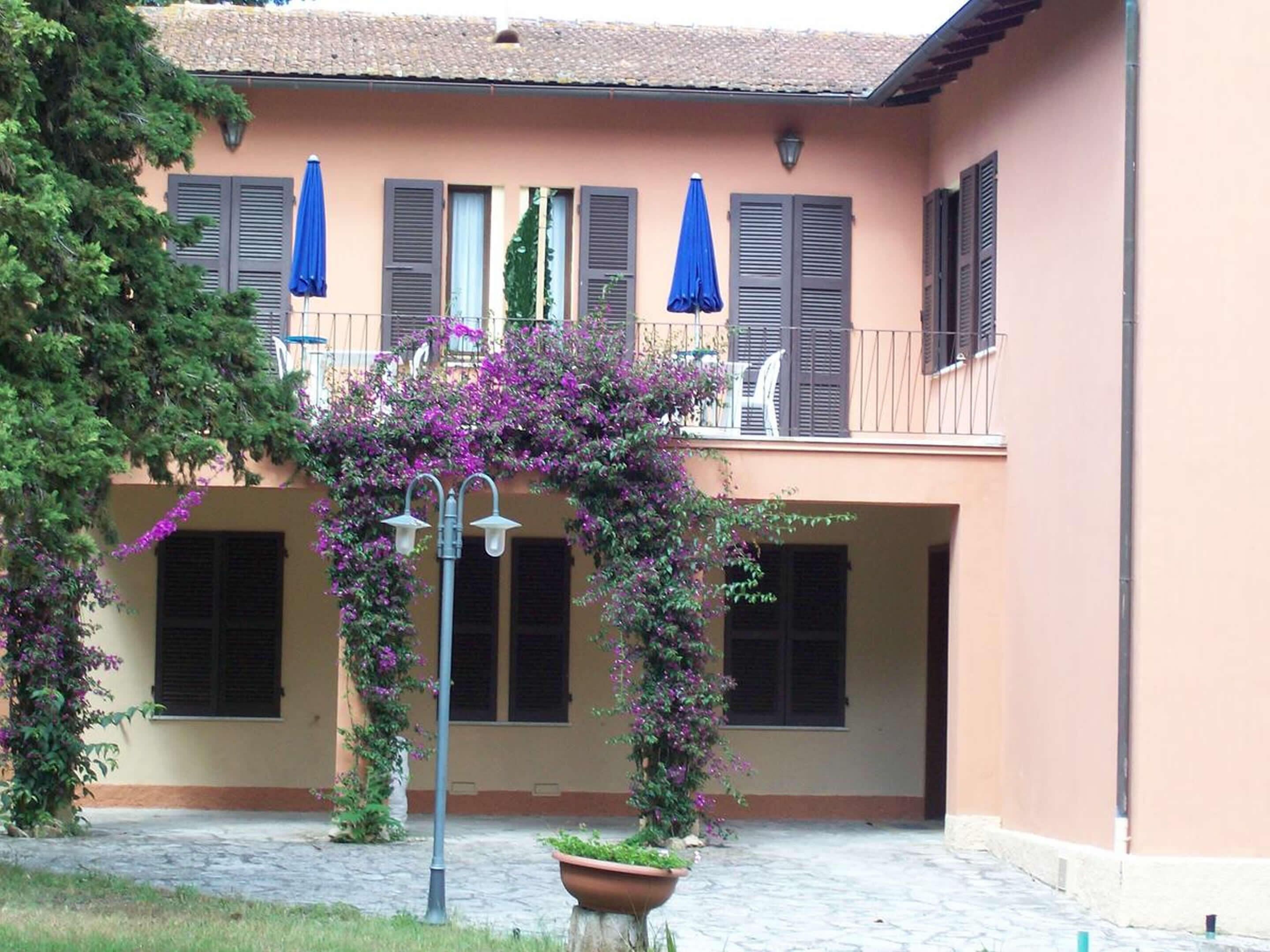 Un edifici amb un balcó, plantes en testos i paraigües blaus.