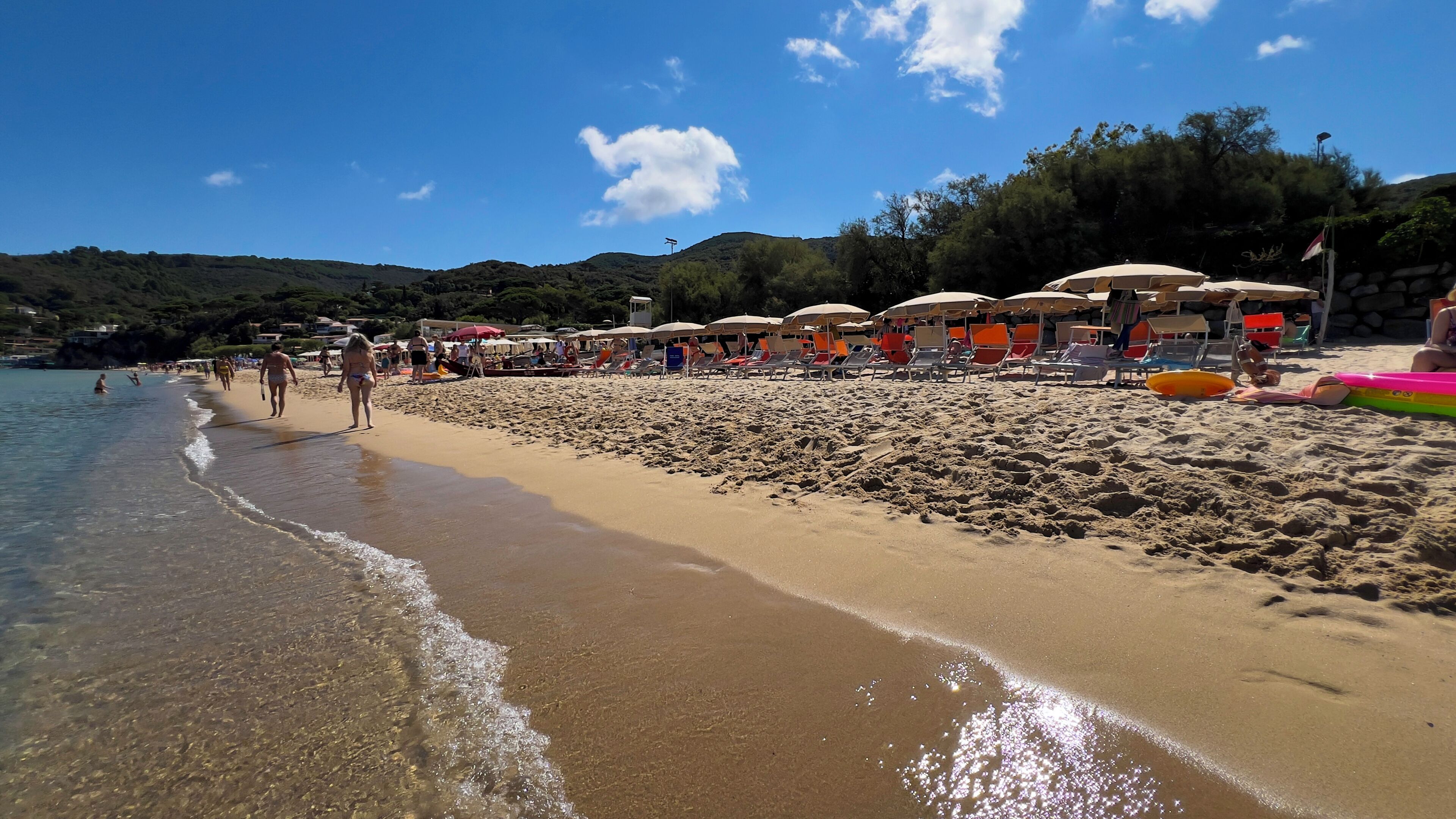 A beach with clear water, umbrellas, and beach chairs.