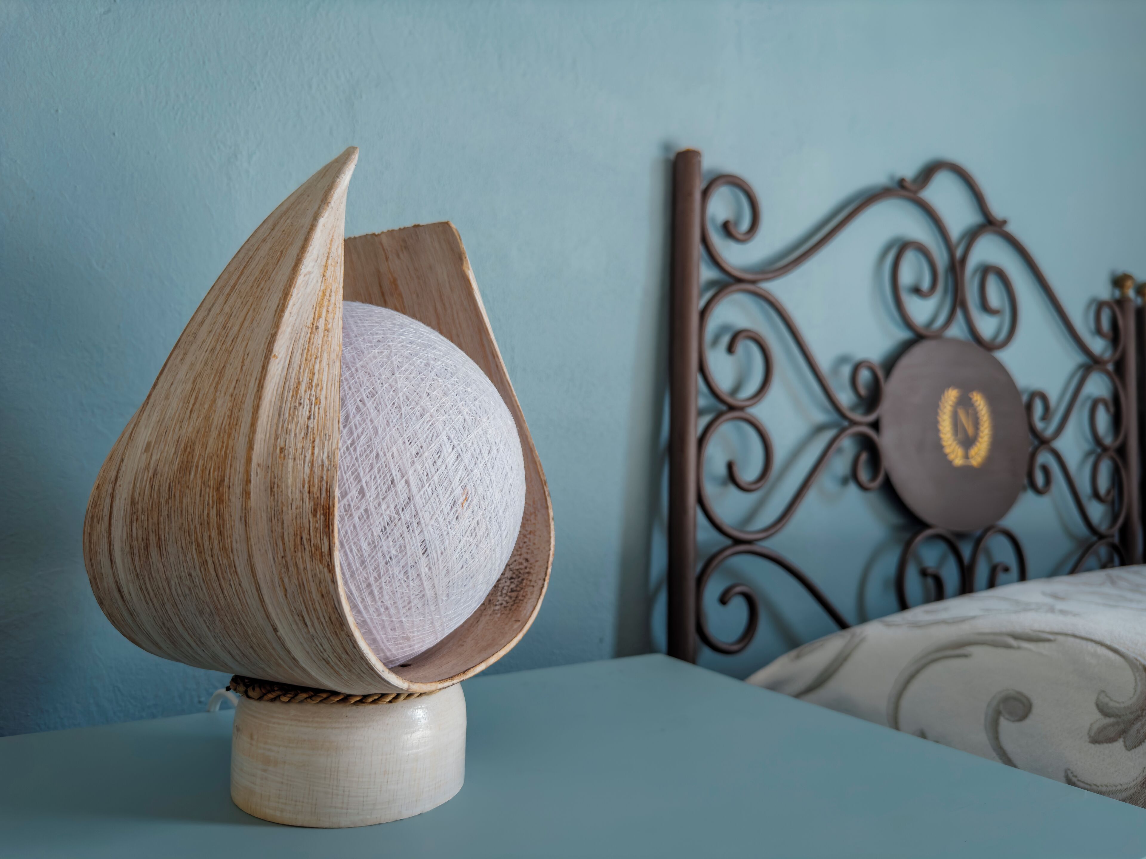 Uma cama com cabeceira decorativa e um objeto de madeira com um objeto esférico em cima.