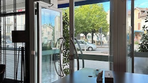 Zona d'entrada d'hotel amb un taulell de recepció de fusta, una campana i vista al carrer.