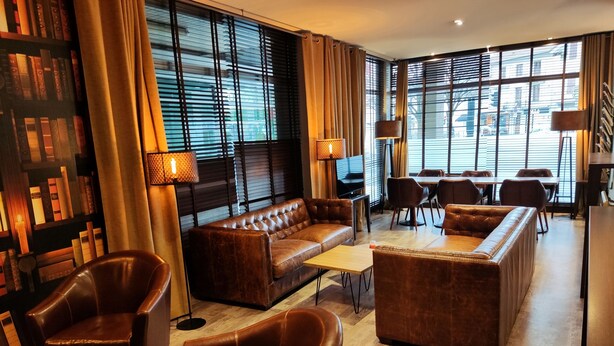 Un rebedor modern d'hotel amb sofàs de cuir, una televisió i una zona de menjador.