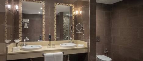 A modern bathroom with two sinks, a large mirror, and a toilet.