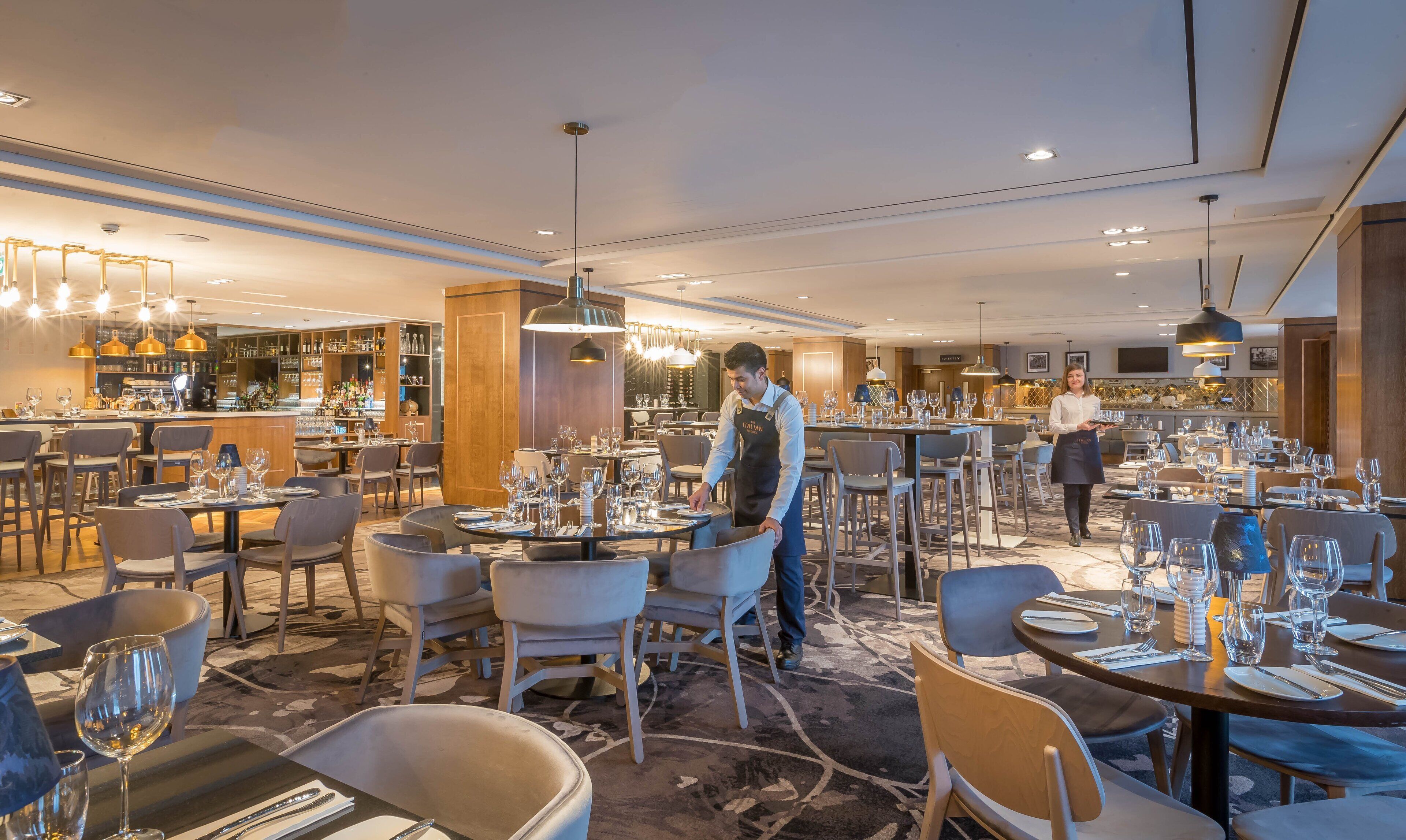 A spacious restaurant with multiple dining areas, a bar, and a well-lit interior.