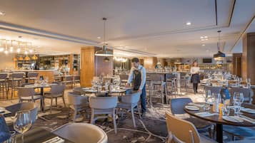 A spacious restaurant with multiple dining areas, a bar, and a well-lit interior.