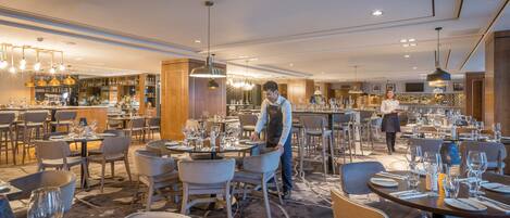 Un restaurante espacioso con varias zonas de comedor, un bar y un interior bien iluminado.
