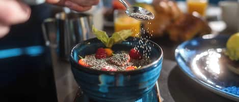 A dining table with a bowl of food, a spoon, and a cup.