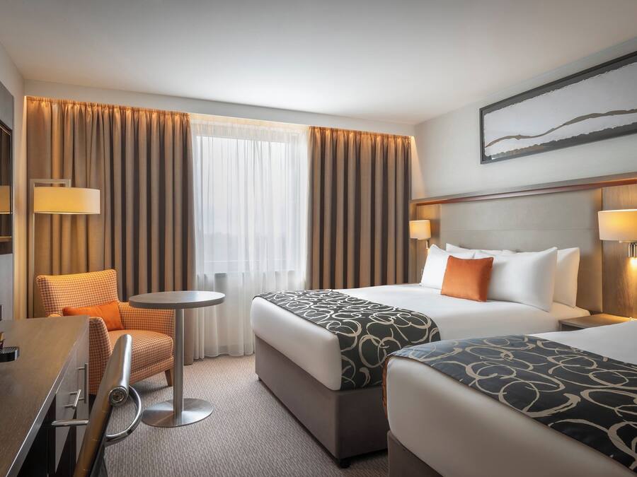 A hotel room with two beds, a sofa, a small round table, and a TV.