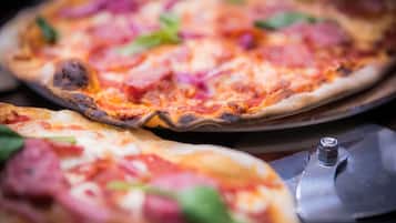 Una pizza con ingredientes visibles y un cortador de pizza sobre una bandeja.