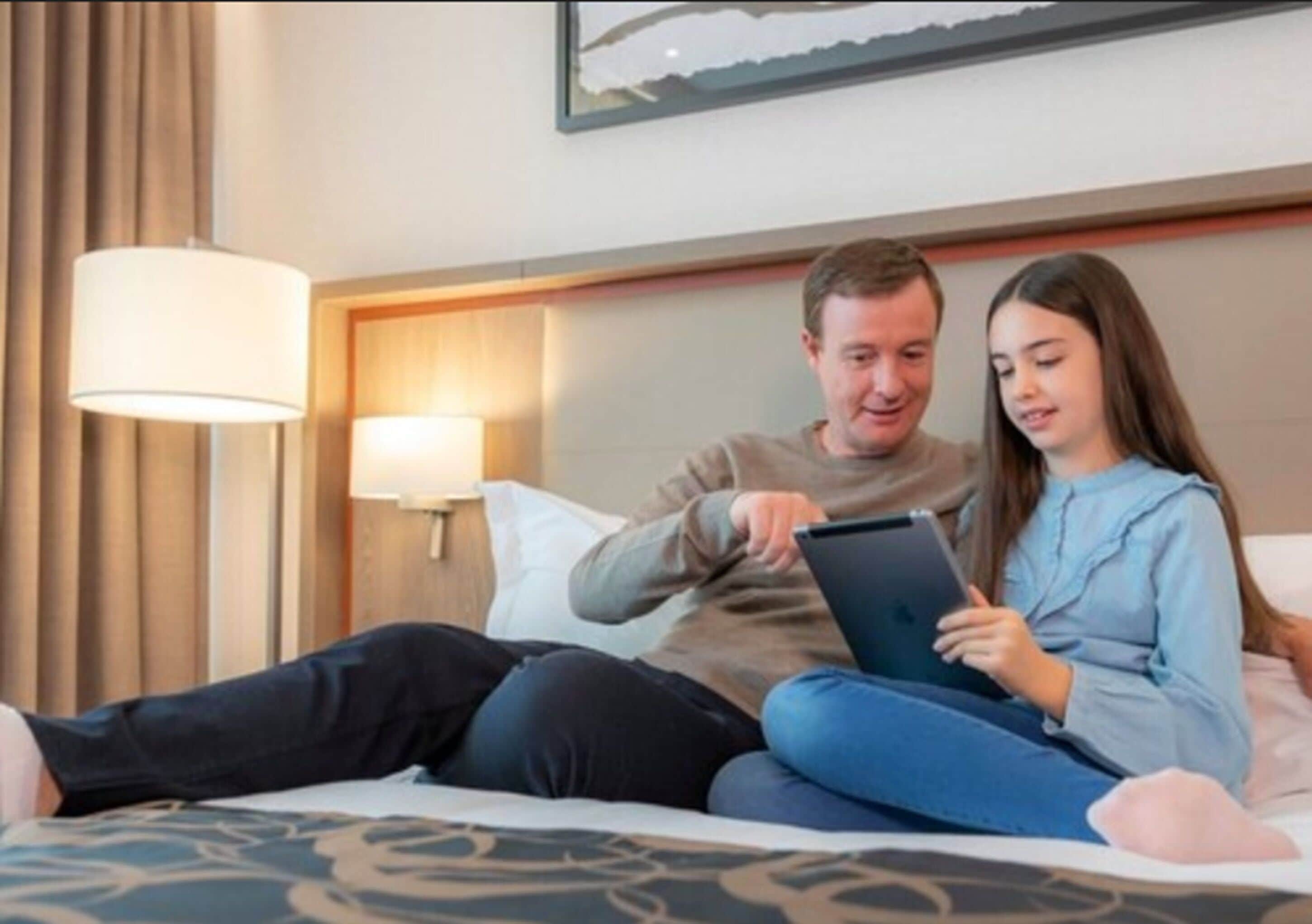 Una habitación de hotel con cama, lámpara de noche e imagen colgada en la pared.