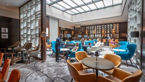 A spacious lobby with a high ceiling, modern seating arrangements, and a bar area.