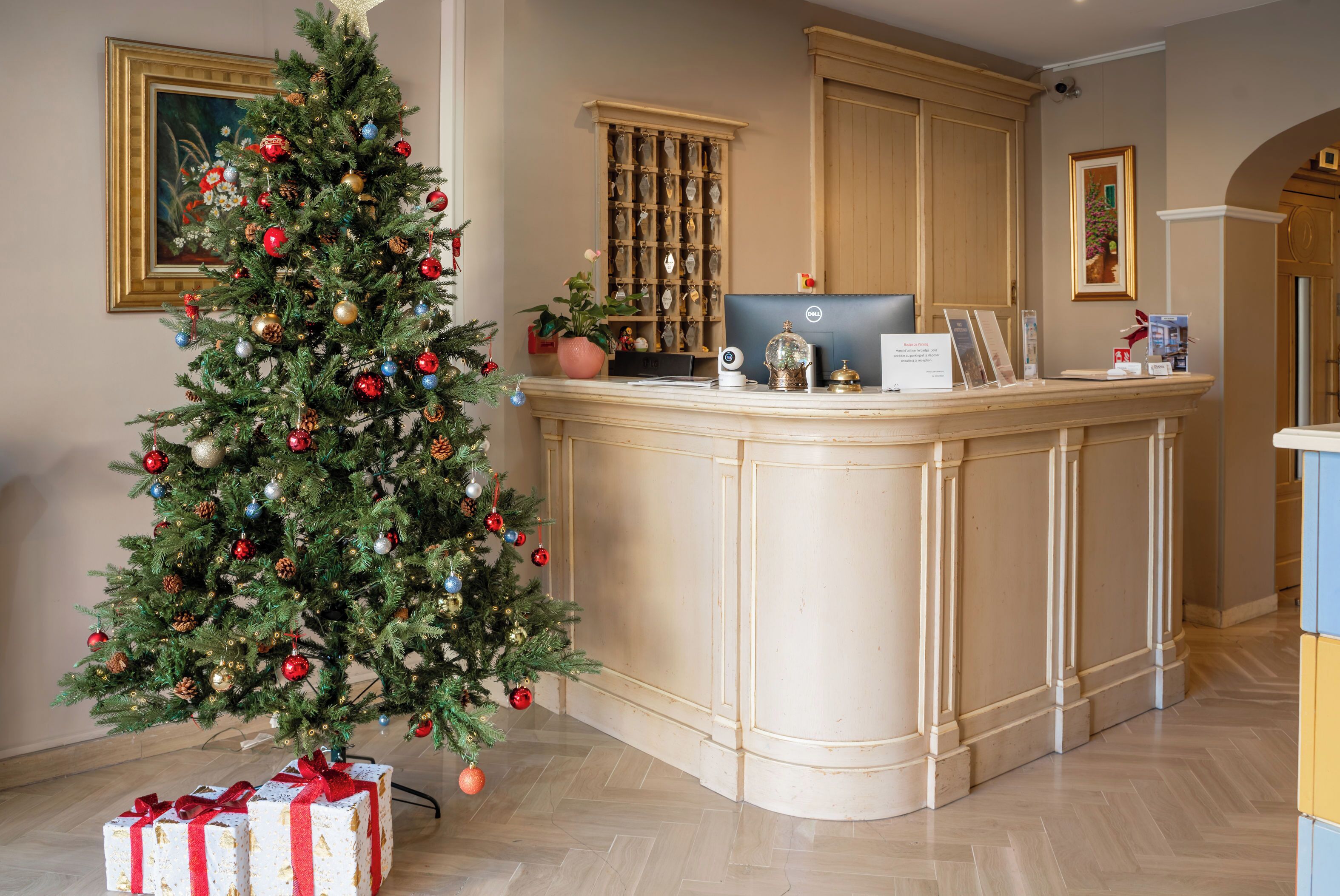 Un espace d’accueil avec un sapin de Noël, un bureau avec un ordinateur et des œuvres d’art encadrées accrochées aux murs.