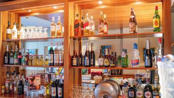 A bar with multiple shelves stocked with various bottles and glasses.