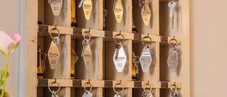 A wooden key rack with numbered key holders, each labeled with a name and number.
