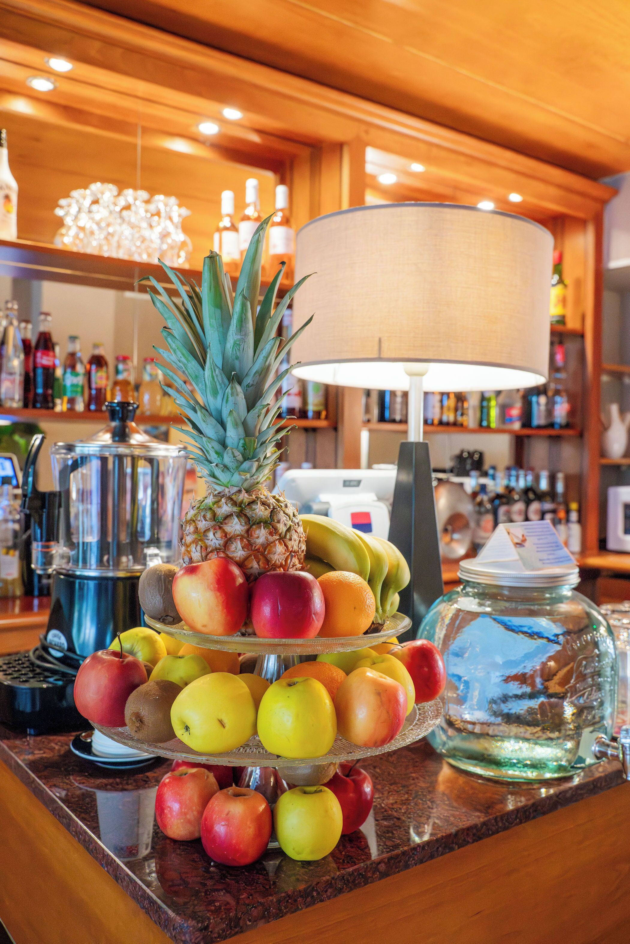 Exhibición de frutas con una piña, manzanas y plátanos sobre una barra.