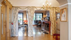 A hallway with wooden flooring, a dining area with a bar, and a large window. - Hotel Diana (Vence)