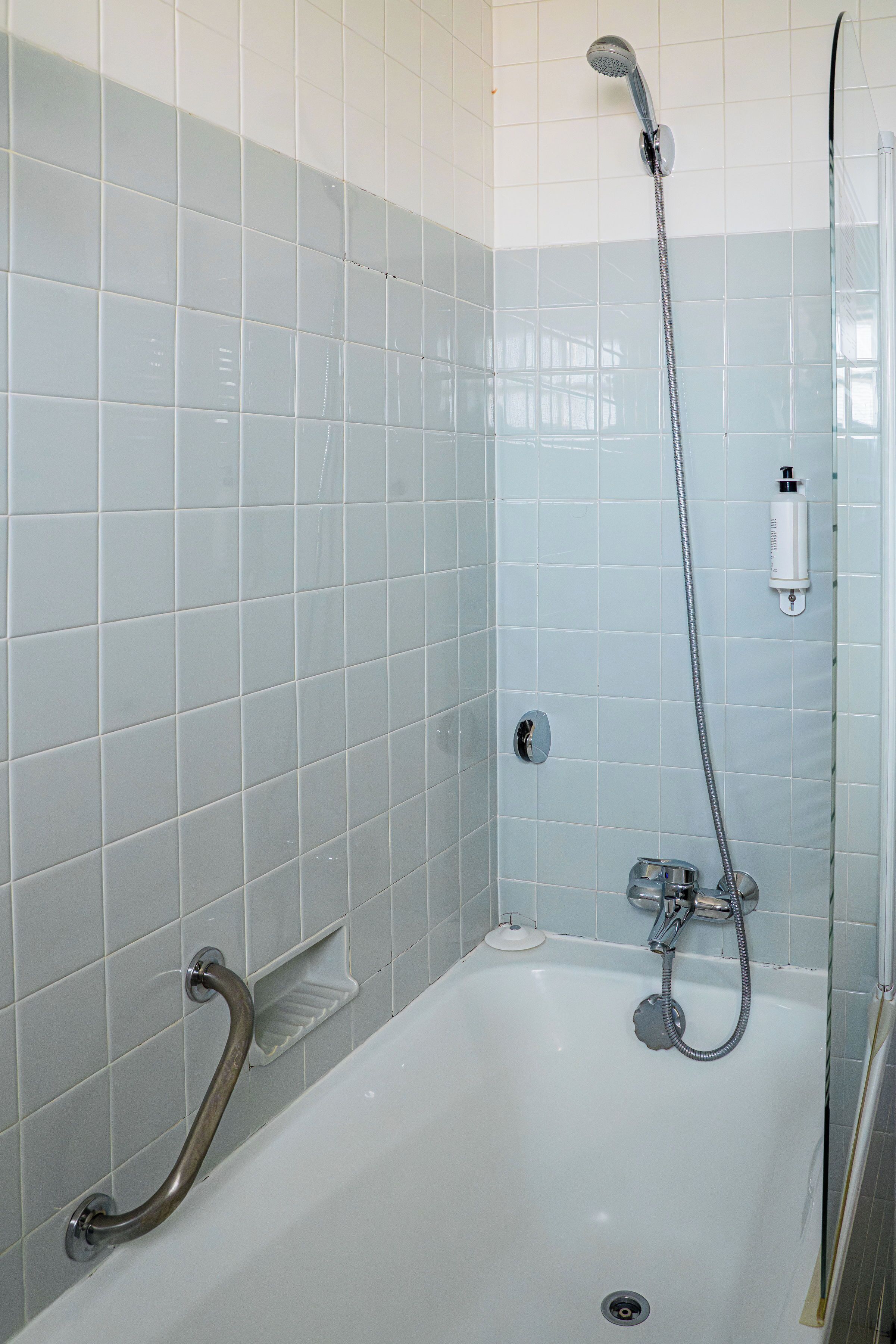 A bathroom with a bathtub, a shower, and a grab bar.