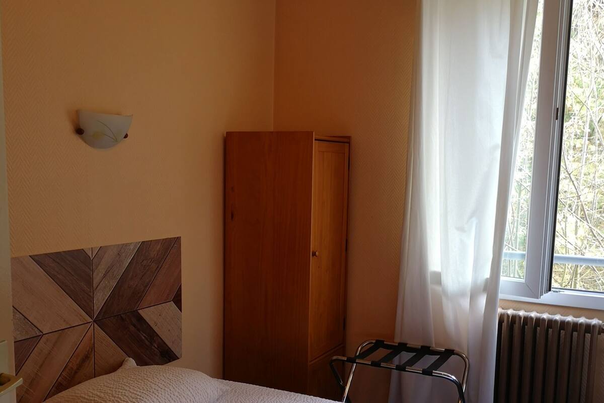 A bedroom with a bed, a wardrobe, a radiator, and a window with curtains.