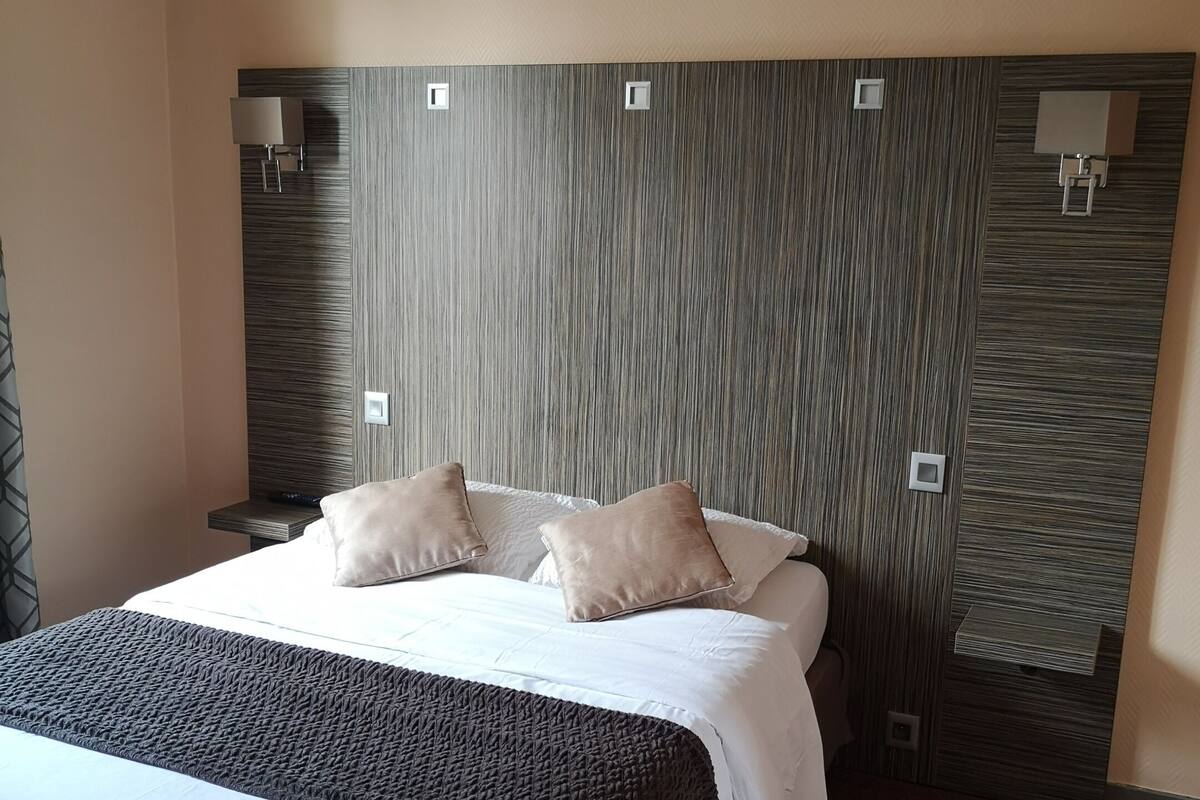 A hotel room with a large bed, two bedside tables, and a headboard with built-in lighting.