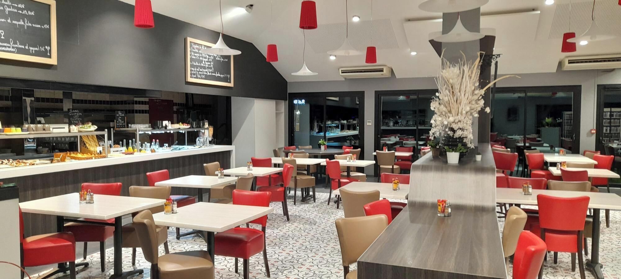 A modern restaurant with a central bar, red and beige chairs, and a patterned floor.