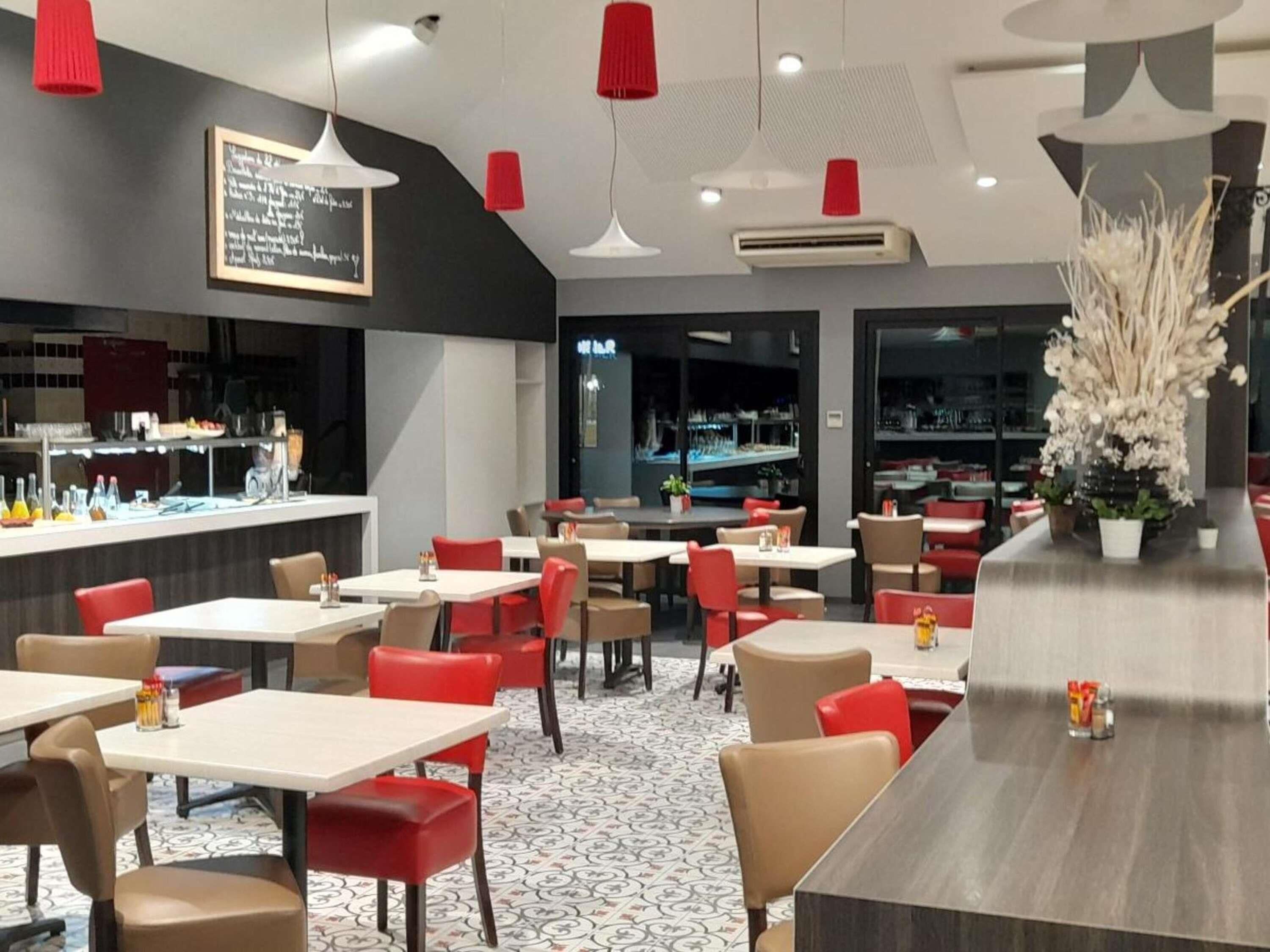 A modern restaurant interior with tables and chairs, a bar area, and a chalkboard menu.
