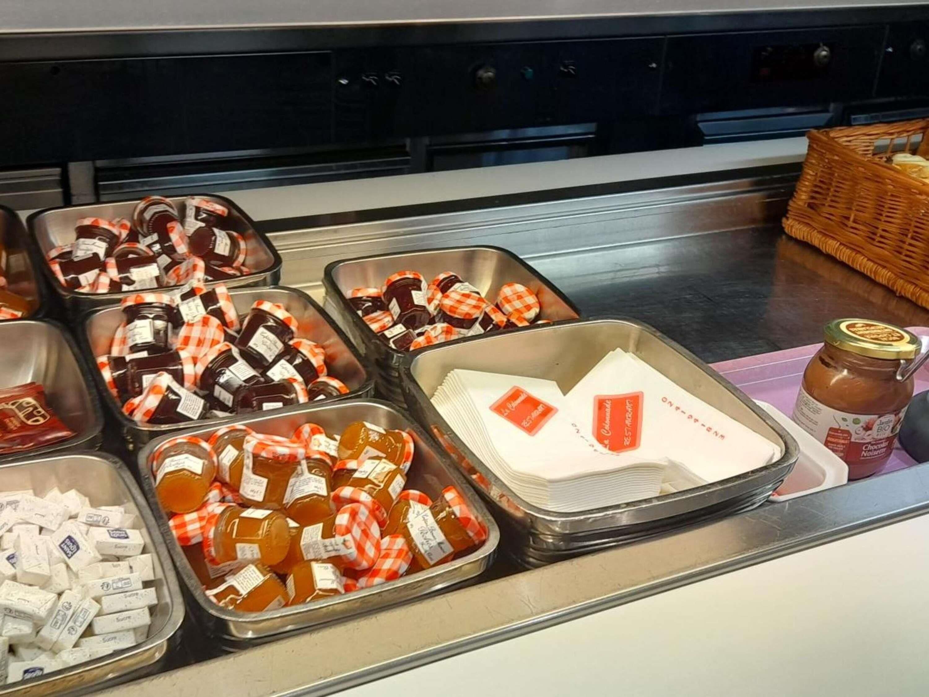 A buffet with various food items in trays, including jars of sauces and condiments.