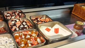 A buffet with various food items in trays, including jars of sauces and condiments.
