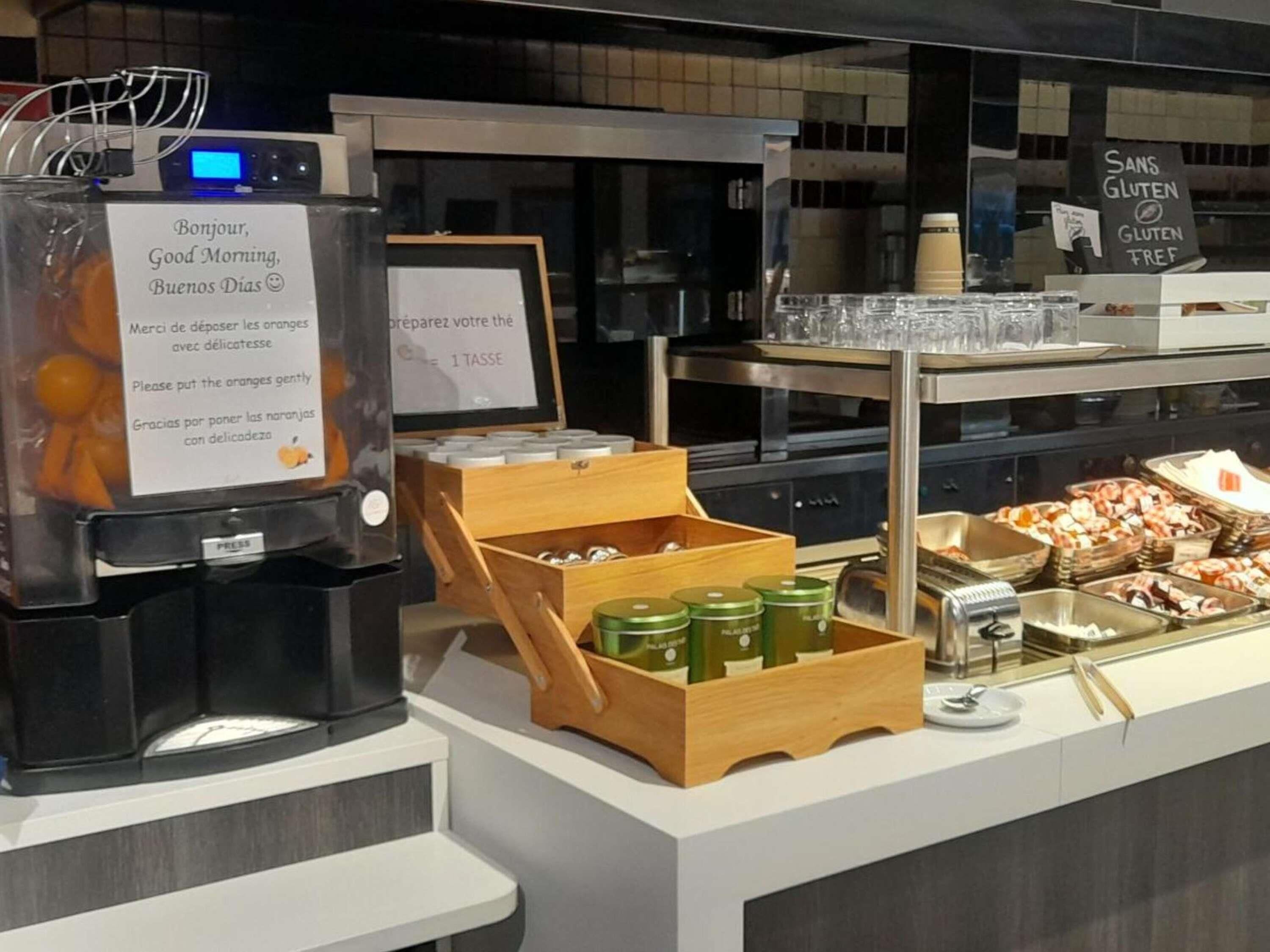 A buffet setup with labeled containers, a coffee machine, and a sign indicating gluten-free options.