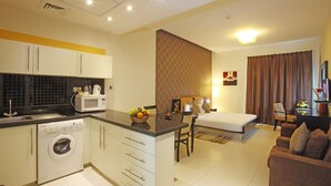 A compact hotel room with a kitchenette, a dining area, and a bed. - Royal Ascot Hotel Apartment (Dubai)