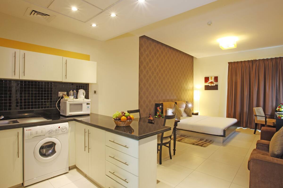 Une chambre d’hôtel compacte comprenant un coin cuisine, un espace repas et un lit.