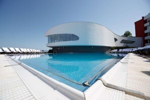 A modern building with a pool, surrounded by lounge chairs. - Zenith Hotel Conference & Spa (Constanta)