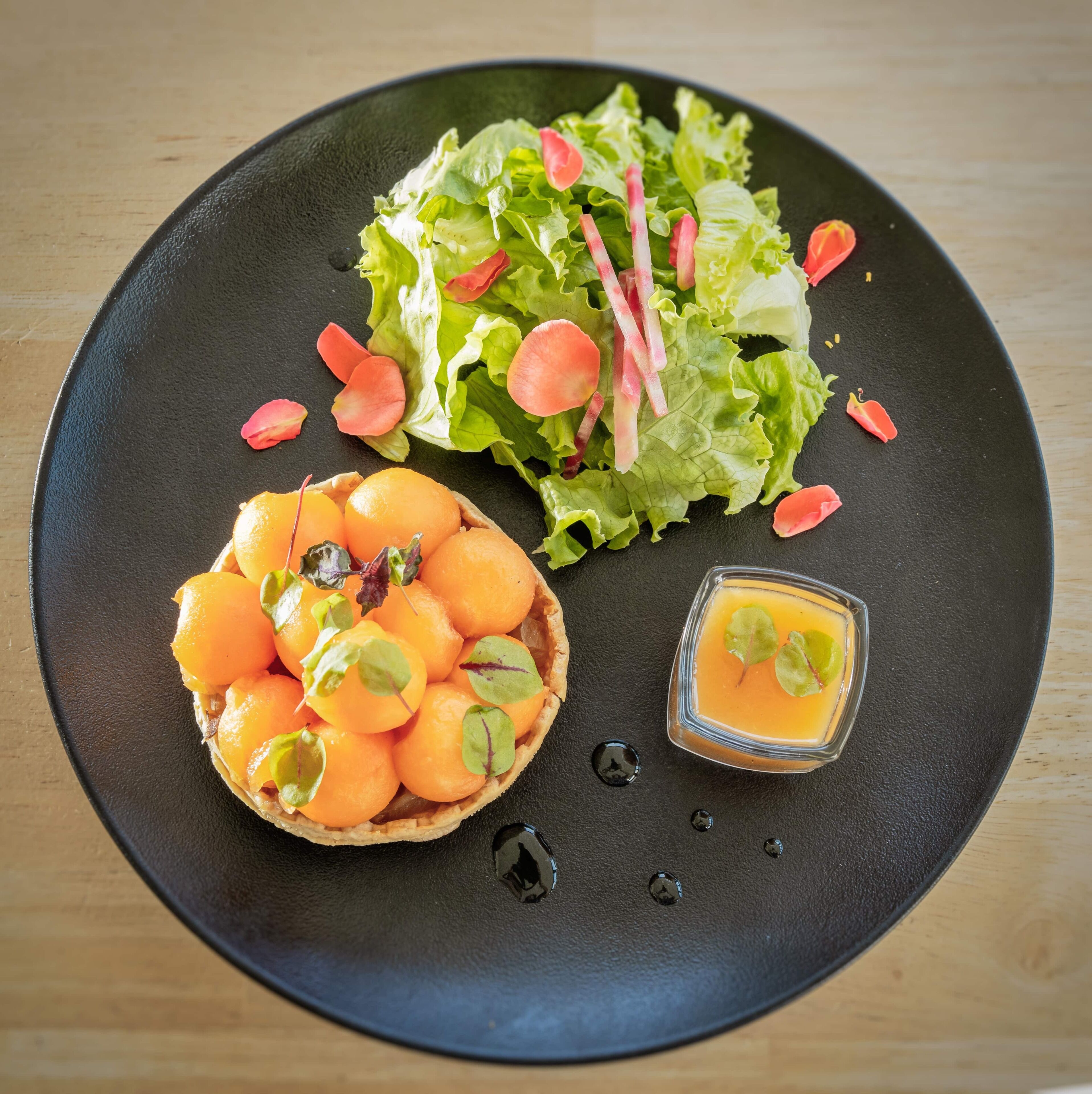 A plate with a salad, a tart, and a small glass of juice.
