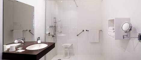A modern bathroom with a glass-enclosed shower, a large mirror, and a white sink.