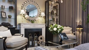 A well-furnished living room with a fireplace, a round mirror, and a coffee table with a vase of flowers. - Hotel Monge (Paris)