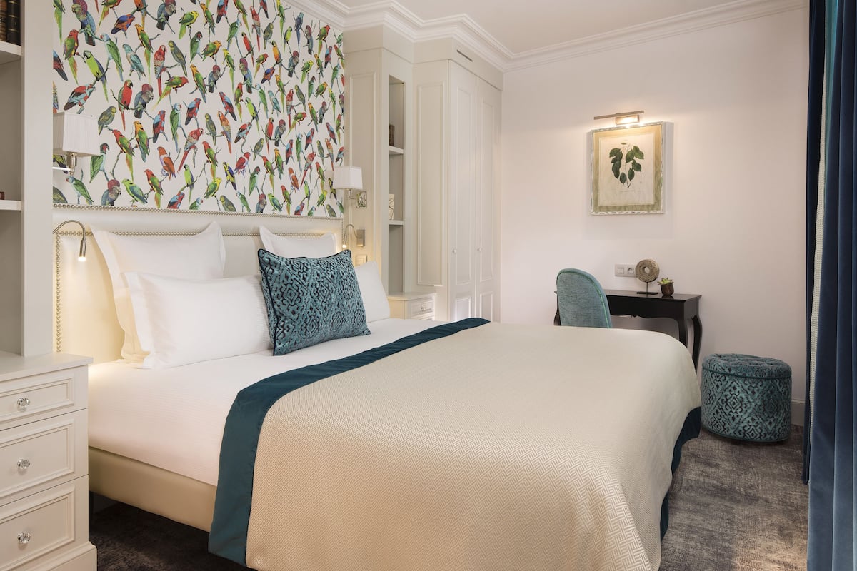A neatly arranged bedroom with a large bed, a bedside table, a chair, and a wardrobe.