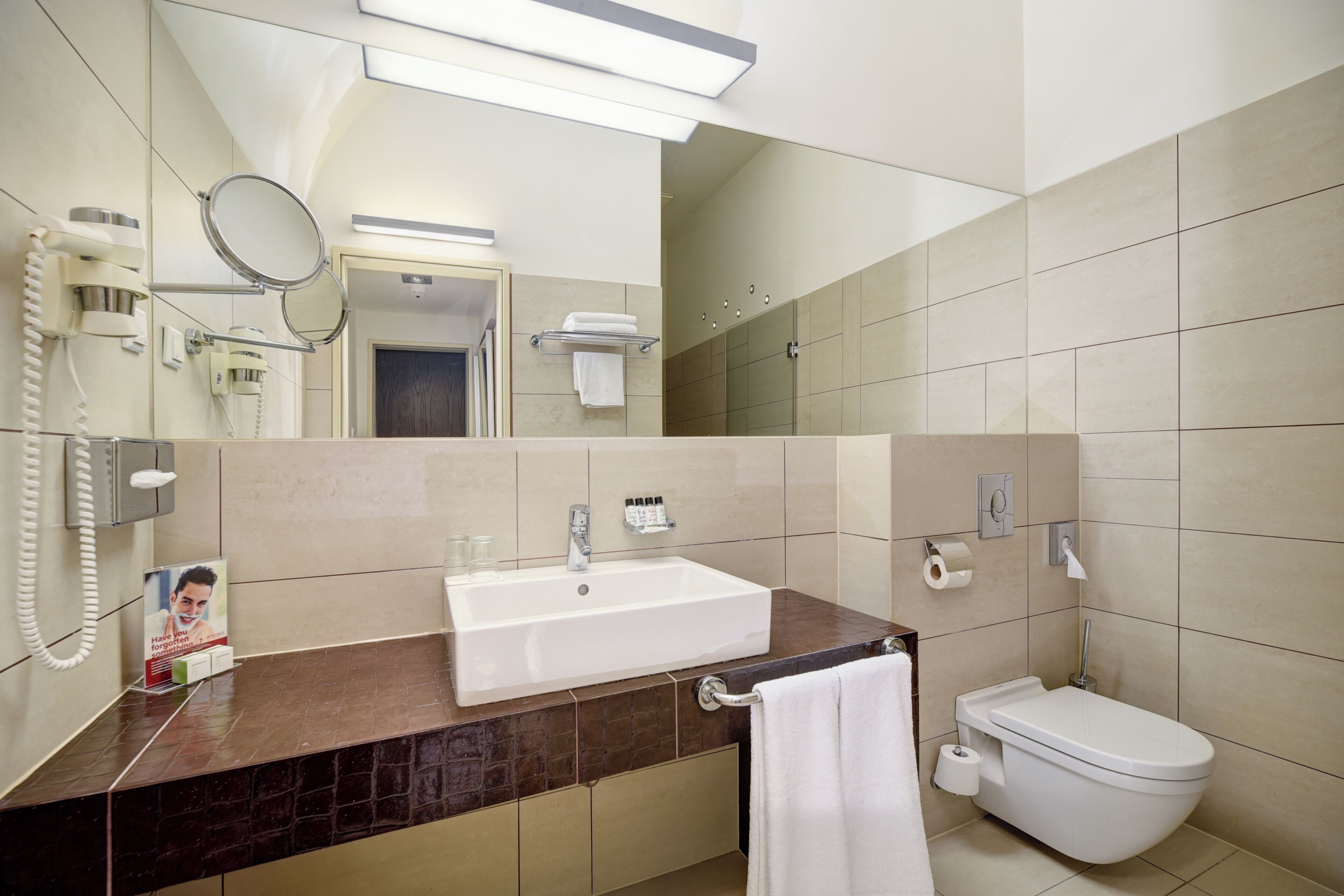 A bathroom with a sink, toilet, mirror, and a towel rack.