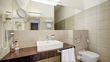 A bathroom with a sink, toilet, mirror, and a towel rack.