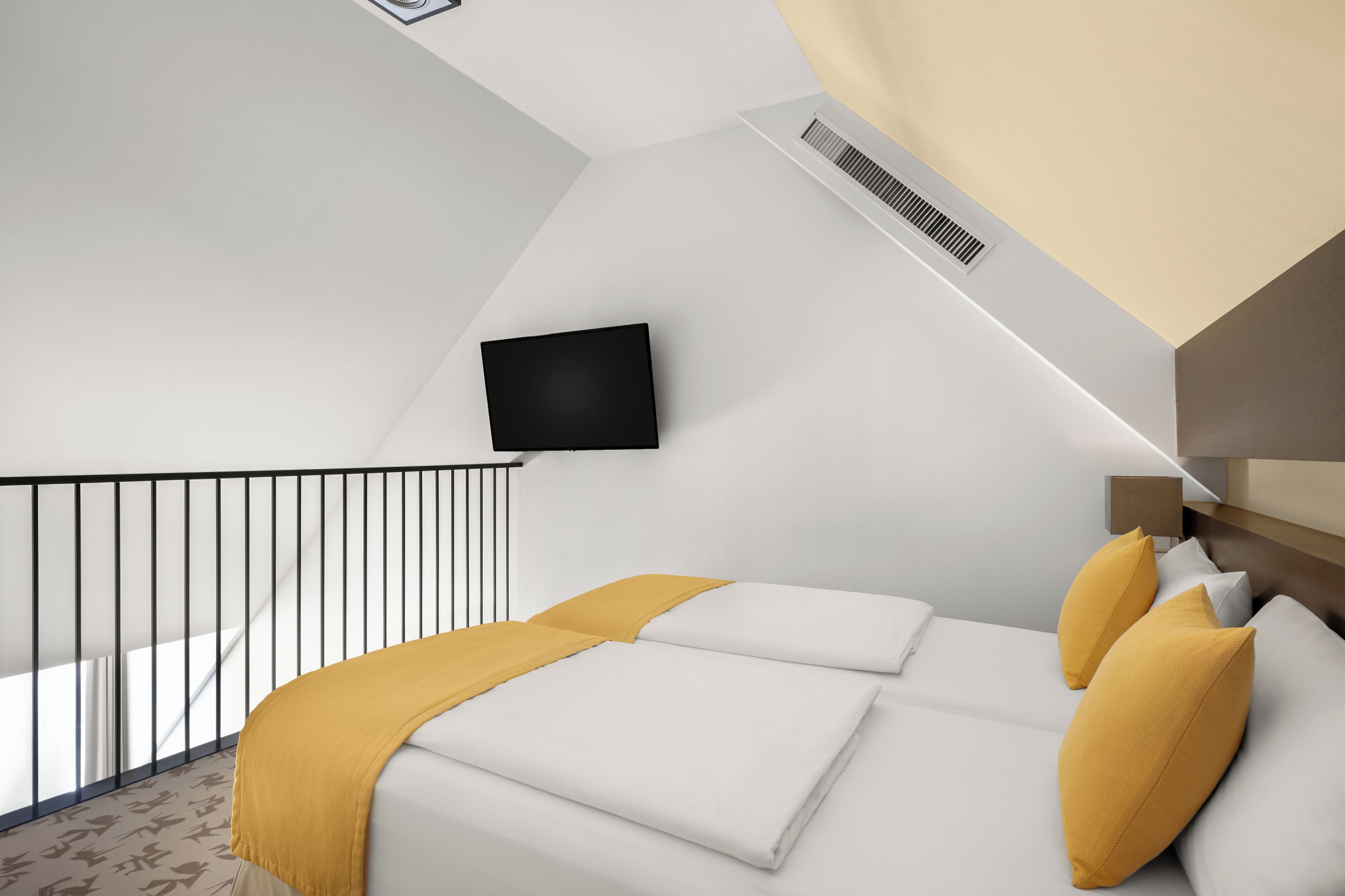 A modern hotel room with a bed, a TV mounted on the wall, a balcony, and a ceiling vent.
